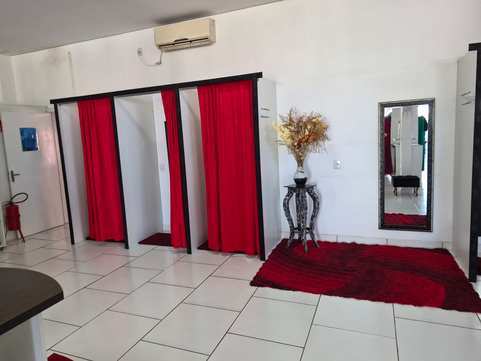 Provadores com cortinas vermelhas e espelho amplo