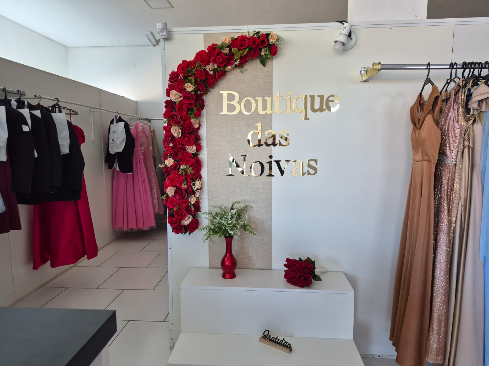 Interior da Boutique das Noivas com letreiro dourado e arco de rosas